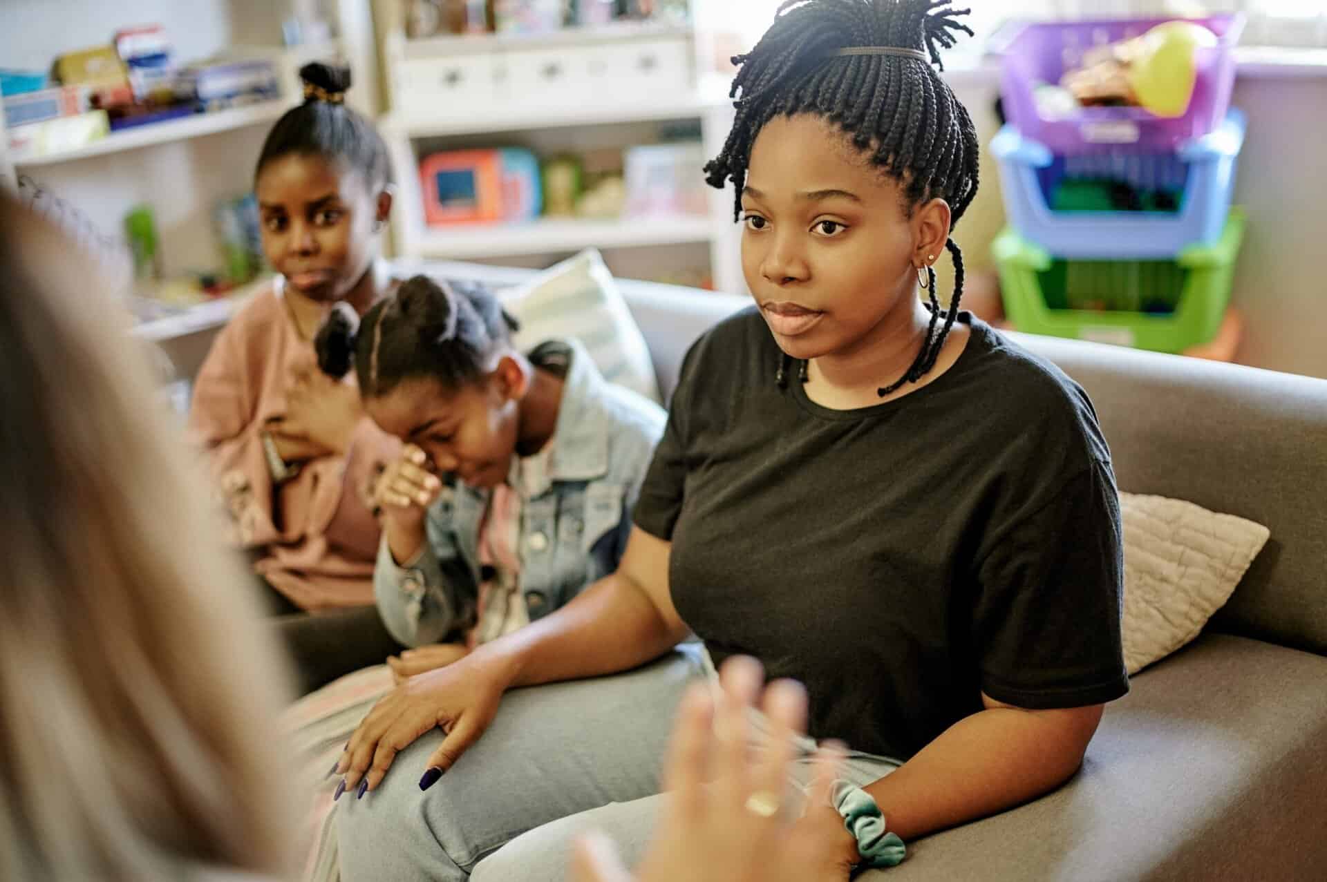 A family sitting together on a sofa during a clinical intake or therapy session, focusing on building a unified support system for recovery.
